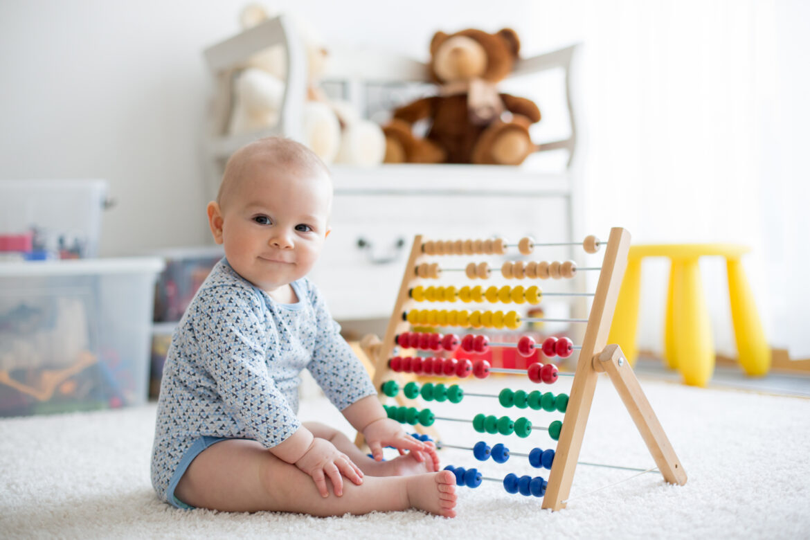 Cute little baby boy, playing with abacus at home